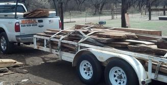A trailer with wood on it is being loaded.