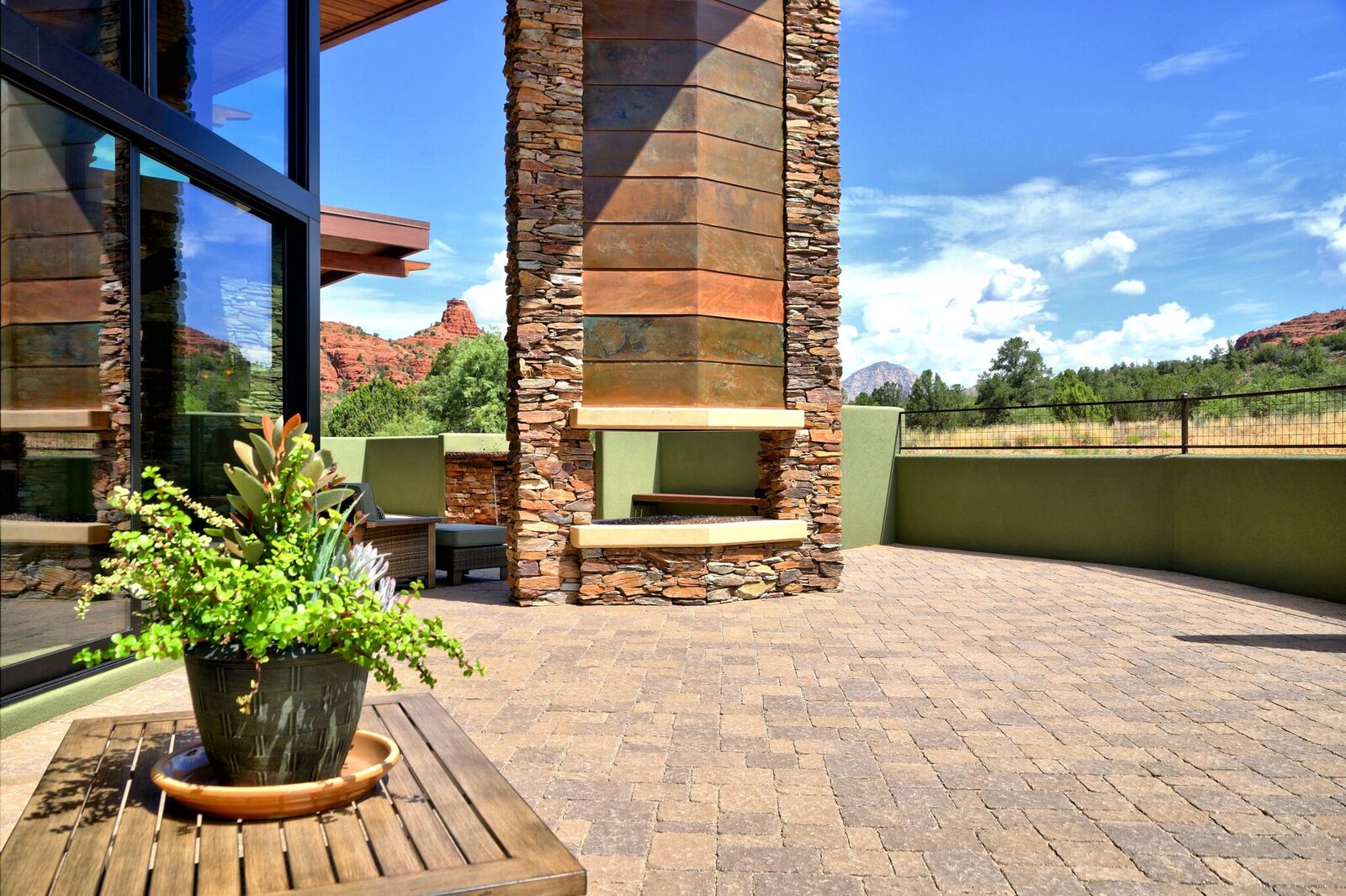 A patio with a fireplace and plants in the middle of it.