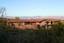 A large brown house with mountains in the background.