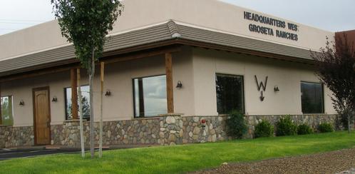 A building with a grassy area and trees in the background.