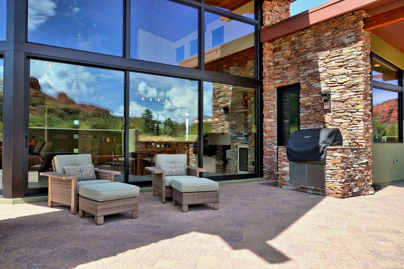 A patio with chairs and a grill in the middle of it.