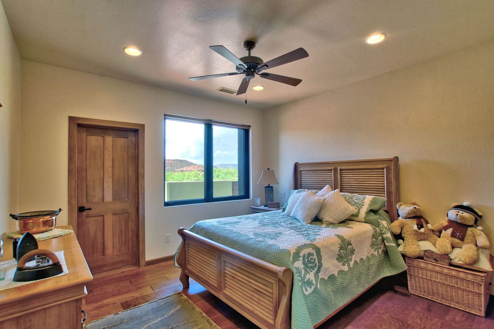 A bedroom with a bed, ceiling fan and door.